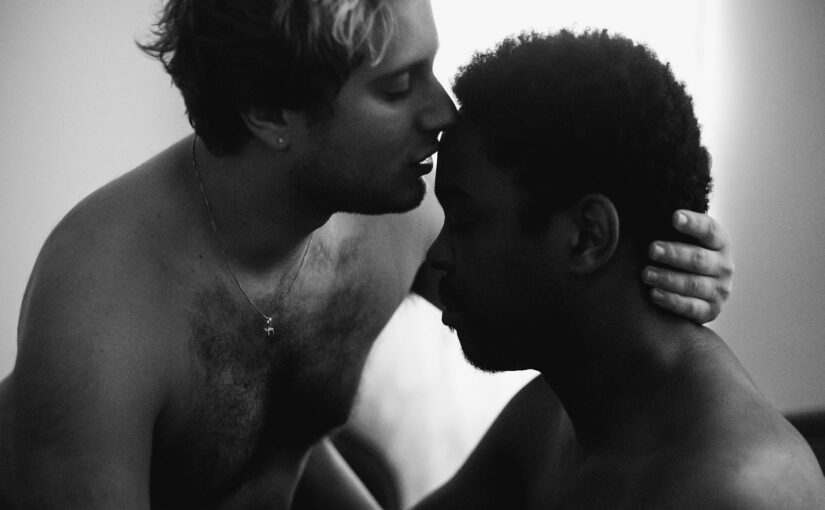 Grayscale Photo of a Man Kissing Another Man on the Forehead